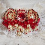 Broche Rubis brodée avec trois cabochons Ivoire et Rouge à laquelle s’ajoute des toupies aux couleurs Cristal, Burgundy et Garnet, des perles nacrées et opaque. Monté sur une dentelle et une broche